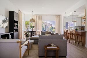 a living room with a gray couch and a kitchen at The Sunset Hideaway by Roav Retreats in Cathedral City