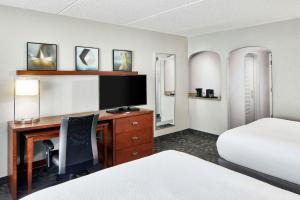 a hotel room with a desk with a tv and a bed at Courtyard Rochester East / Penfield in Rochester +18 photos