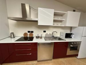 een keuken met rode kasten en een spoelbak bij Alvina's House in Aosta