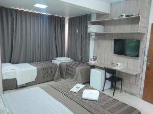 a hotel room with two beds and a desk at Hotel Conexão Pampulha in Belo Horizonte