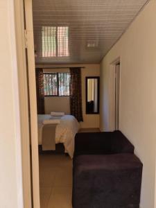 a bedroom with a bed and a couch and a window at Hideout in Highlands in Harare
