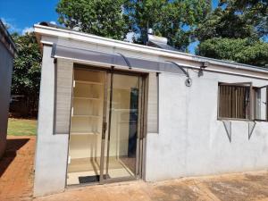 a small white building with sliding glass doors at Hideout in Highlands in Harare