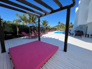 un banco rosa en una terraza junto a una piscina en Bombinhas Blue Suítes, en Bombinhas
