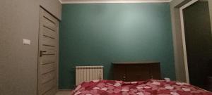 a bedroom with a green wall and a bed with pink sheets at Biały domek z ogrodem, 3 sypialnie in Bydgoszcz