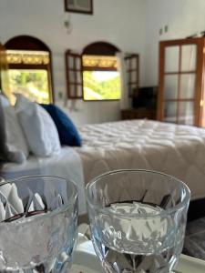 two glass bowls sitting on a table next to a bed at Pousada Altos do Vale in Mendes +18 photos