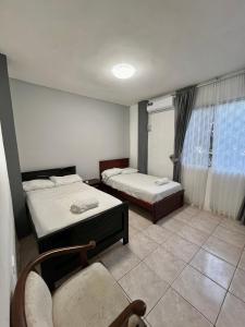 a room with two beds and a chair and a window at 6 habitaciones, 10 camas, amplio y céntrico, 3 parqueos in Machala