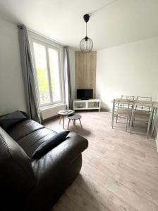 ein Wohnzimmer mit einer Ledercouch und einem Tisch in der Unterkunft Appartement cosy Disneyland & Paris in Neuilly-sur-Marne + 1 Foto