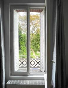 ein offenes Fenster mit Blick auf einen Park in der Unterkunft Appartement cosy Disneyland & Paris in Neuilly-sur-Marne
