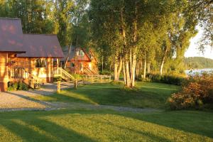 a log cabin with a fence in front of a yard at Riverside Cabins at Susitna River Lodge in Talkeetna