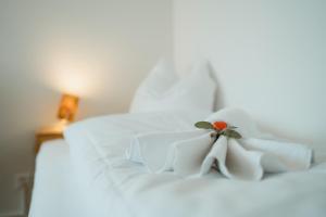a white bed with white sheets and a flower on it at Apartment Alpenblick in Amden +14 photos