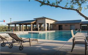 a swimming pool with chairs and a building at Spacious 3BR Home - Pool, Playground, EV Station L2, Near Freeway, Free Parking in Tucson