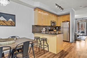 a kitchen with wooden cabinets and a table and chairs at Mystic Chalet- Views, Pool, Hot Tub, Pets - managed by Little Sister Getaways in Canmore