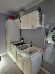 a kitchen with white cabinets and a sink at Central Apartment 2 bedrooms Business and Travel Lounge in Craiova