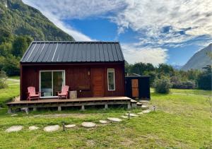 a small cabin in a field with two chairs at Cabañas Refugio Río Roberto in Villa Santa Lucía