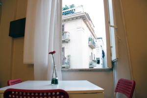 une table et des chaises avec une fenêtre donnant sur un bâtiment dans l'établissement Castelnuovo Rooms, à Palerme