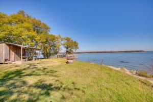 a house on a hill next to a body of water at Boat Ramp and Fire Pit Lake Tawakoni Group Retreat! in Quinlan