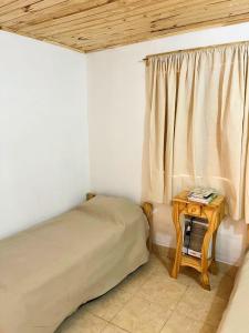 ein Schlafzimmer mit einem Bett und einem Tisch mit einem Fenster in der Unterkunft Cabaña La escondida I in Purmamarca