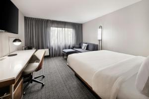 a hotel room with a large bed and a chair at Courtyard Mobile in Mobile +19 photos