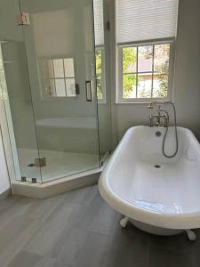 a bathroom with a tub and a shower and a sink at Gator Grove - Colonial House - Brand New Build! in Gainesville