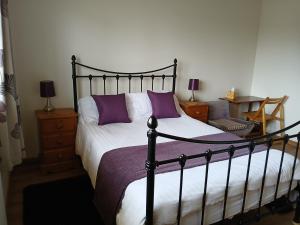 a bedroom with a black and white bed with purple pillows at Woodlands Peaceful Bedrooms in Hemingford Grey