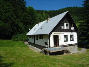 una casa bianca con un tetto nero in un campo di Chata Tanvaldský Špičák a Tanvald
