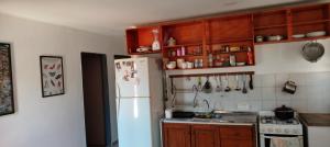 a kitchen with a white refrigerator and wooden cabinets at La casa de Tilili in Puerto Iguazú +5 photos