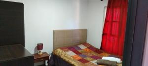 a bedroom with a bed and a red curtain at La casa de Tilili in Puerto Iguazú