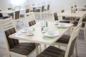 een witte tafel met borden, bekers en stoelen bij Complex Oktyabrskiy in Stavropol