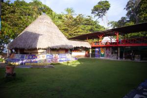 a building with a thatched roof and a green yard at Rocking J's in Puerto Viejo