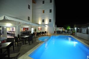 a swimming pool with tables and chairs next to a building at Ialysos City Hotel in Ialysos