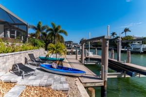 マルコ・アイランドにある"The Lighthouse" l Gorgeous Waterfront 3 Bed with Quick Access to Gulfの水辺にボートと椅子が置かれた桟橋