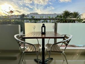 een tafel met een fles en twee glazen op een balkon bij Cozy Apartament Maspalomas in San Bartolomé