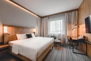a hotel room with a large bed and a desk at Courtyard by Marriott Warsaw Airport in Warsaw +37 photos