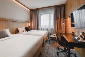 a hotel room with two beds and a desk at Courtyard by Marriott Warsaw Airport in Warsaw