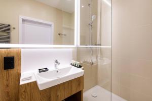 a bathroom with a sink and a shower at Courtyard by Marriott Warsaw Airport in Warsaw
