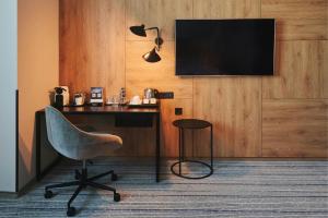 a room with a desk and a chair and a television at Courtyard by Marriott Warsaw Airport in Warsaw