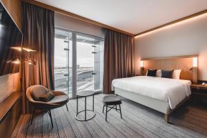 a hotel room with a bed and a chair at Courtyard by Marriott Warsaw Airport in Warsaw