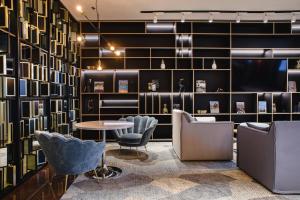 a lobby with chairs and a table and a wall of books at Courtyard by Marriott Warsaw Airport in Warsaw