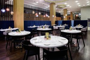 a dining room with white tables and black chairs at Courtyard by Marriott Warsaw Airport in Warsaw