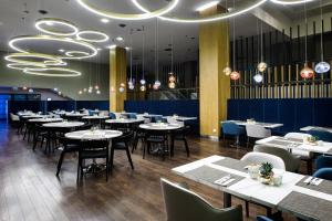 a dining room with tables and chairs and chandeliers at Courtyard by Marriott Warsaw Airport in Warsaw