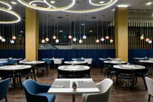 a restaurant with tables and chairs and chandeliers at Courtyard by Marriott Warsaw Airport in Warsaw