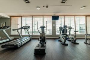 a gym with several tread machines in a room with windows at Courtyard by Marriott Warsaw Airport in Warsaw