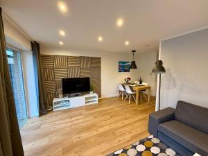 a living room with a couch and a tv and a table at TelmiHome Brüggen, moderne Ferienwohnung mit Sonnenterrasse & Glasfaser-WLAN in Brüggen