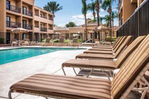 a row of lounge chairs next to a swimming pool at a resort at Courtyard Tucson Airport in Tucson