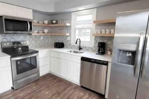 a kitchen with white cabinets and a stainless steel refrigerator at Beechwood by the Bay Dog Friendly in Wildwood Highlands Beach