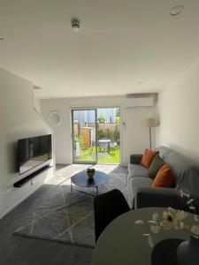 ein Wohnzimmer mit Sofa und Fernseher in der Unterkunft Mohua Lane Retreat in Christchurch