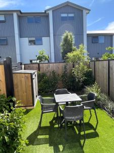einen Garten mit einem Tisch, Stühlen und einem Zaun in der Unterkunft Mohua Lane Retreat in Christchurch