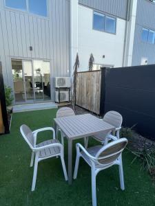 une table de pique-nique et deux chaises sur une pelouse dans l'établissement Mohua Lane Urban Paradise, à Christchurch
