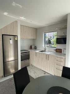 une cuisine avec un réfrigérateur en acier inoxydable et une table dans l'établissement Mohua Lane Urban Paradise, à Christchurch