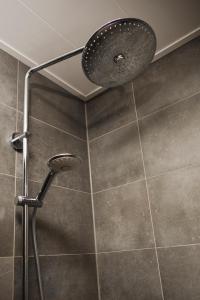 a shower with a shower head in a bathroom at Vakantiewoning de Boshoorn in Serooskerke